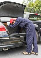 mecânico substituindo o pneu sobressalente na parte de trás do carro foto