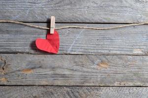 coração vermelho pendurado no varal. em fundo de madeira velho. foto