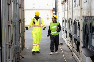 jovens trabalhadores trabalhando em um armazém, engenheiros industriais, supervisores de segurança e capatazes em capacetes e coletes de segurança andando no depósito do terminal de contêineres de carga. foto