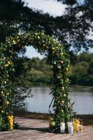 arco de casamento é decorado com folhas verdes e limões. foto