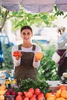 jovem vendedora segurando tomates caseiros nas mãos foto