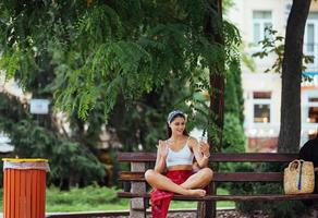 mulher usando um smartphone no parque sentado em um banco foto