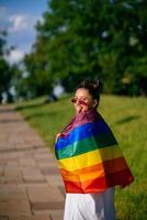 jovem com bandeira do orgulho lgbt andando no parque. foto