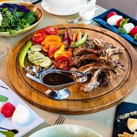 kebab e vegetais em prato redondo de madeira giratório foto