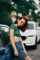 bela jovem elegante de óculos posando perto de carro foto