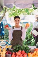 jovem vendedora segurando tomates caseiros nas mãos foto