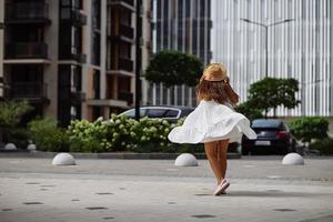 linda mulher bonita de vestido branco andando na rua da cidade foto