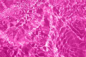 desfocar textura de superfície de água calma transparente de cor roxa transparente turva com respingo, bolha. fundo de ondulação de água roxa brilhante. superfície da água na piscina. brilho de água de bolha roxa. foto