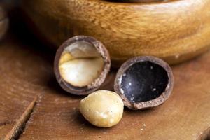 nozes de macadâmia com casca em uma mesa de madeira foto