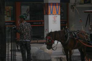 yogyakarta, indonésia, em 23 de outubro de 2022. andong ou carruagem puxada por cavalos com seu cocheiro estacionado em jalan malioboro, esperando passageiros. foto