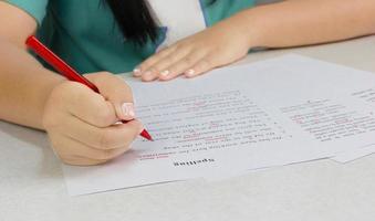 mão segurando caneta vermelha sobre papel de revisão foto