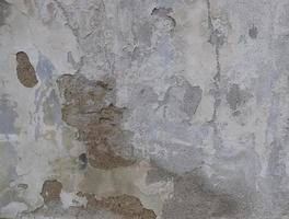 fundo de descascar tinta branca em uma parede velha. fundo de textura de um velho muro feito de gesso cinza. rachaduras. copie o espaço. parede de gesso descascada velha, desmorona. foto