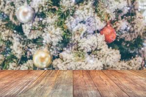 tampo de mesa de madeira vazio com árvore de natal desfocada com fundo claro bokeh foto