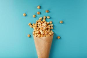 pipoca em esmalte caramelo em um envelope de papel em um fundo azul. foto