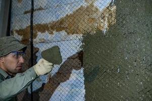 o mestre joga uma solução de concreto líquido na parede, a primeira camada de gesso na parede. foto