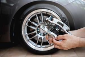 conceito de sistema de parada de corrida de serviço de carro, feche o freio de pinça do carro na mão um homem e a roda do carro em segundo plano foto