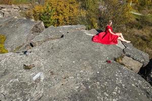 vista aérea na garota de vestido vermelho na rocha ou estrutura arruinada de concreto foto