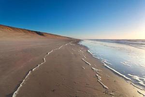 praia de areia e ondas do mar do norte foto