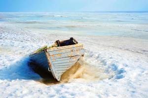 velho barco de madeira azul à beira-mar cercado pela neve foto