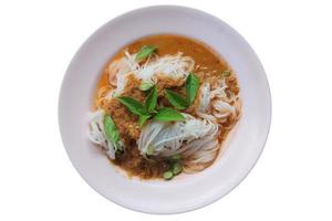 aletria de arroz tailandês a vapor com curry vermelho e legumes. macarrão de arroz em molho de caril de peixe com legumes em um disco rosa isolado no fundo branco. foto