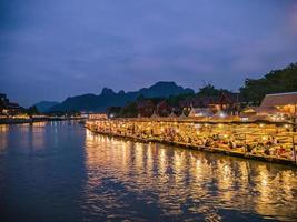 bela vista do rio nam song com restaurante ribeirinho e a montanha à noite na cidade de vangvieng lao.vangvieng cidade a famosa cidade de destino de férias no lao. foto