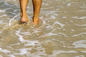 pés humanos andando na praia, turista relaxa nas férias de verão. foto