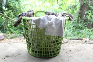 pilha de roupas transbordam cesta de lavanderia de plástico para lavar foto