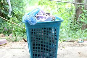pilha de roupas transbordam cesta de lavanderia de plástico para lavar foto