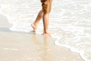 pés humanos andando na praia, turista relaxa nas férias de verão. foto