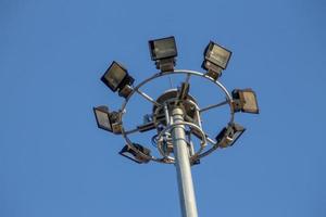 um grande poste elétrico cheio de holofotes no céu azul foto