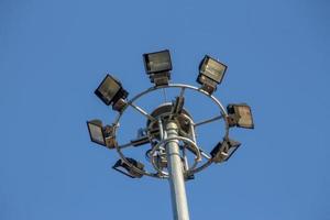 um grande poste elétrico cheio de holofotes no céu azul foto