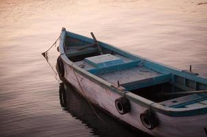velho barco na água, pôr do sol foto