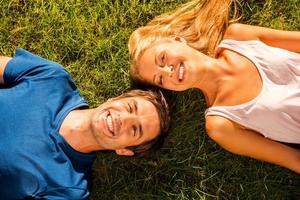 nós amamos a vista superior de verão do feliz casal amoroso deitado na grama verde juntos e sorrindo foto