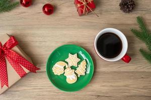 feliz natal com biscoitos caseiros e xícara de café no fundo da mesa de madeira. véspera de natal, festa, feriado e feliz ano novo conceito foto