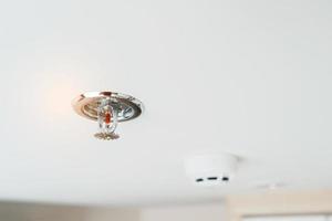 sprinkler de incêndio e detector de sensor de fumaça montado no telhado em casa ou apartamento. conceito de segurança de segurança e conflagração foto