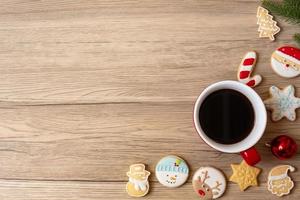 feliz natal com biscoitos caseiros e xícara de café no fundo da mesa de madeira. véspera de natal, festa, feriado e feliz ano novo conceito foto