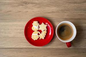 feliz natal com biscoitos caseiros e xícara de café no fundo da mesa de madeira. véspera de natal, festa, feriado e feliz ano novo conceito foto