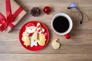 feliz natal com biscoitos caseiros e xícara de café no fundo da mesa de madeira. véspera de natal, festa, feriado e feliz ano novo conceito foto