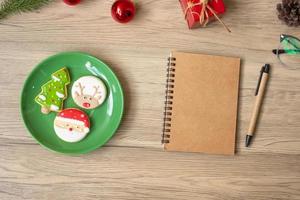 caderno em branco, preto, biscoitos de natal e caneta na mesa de madeira, vista superior e espaço de cópia. natal, feliz ano novo, objetivos, resolução, lista de tarefas, estratégia e conceito de plano foto