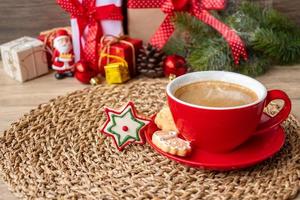 feliz natal com biscoitos caseiros e xícara de café no fundo da mesa de madeira. véspera de natal, festa, feriado e feliz ano novo conceito foto