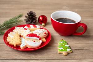 feliz natal com biscoitos caseiros e xícara de café no fundo da mesa de madeira. véspera de natal, festa, feriado e feliz ano novo conceito foto