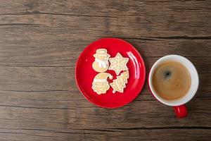 feliz natal com biscoitos caseiros e xícara de café no fundo da mesa de madeira. véspera de natal, festa, feriado e feliz ano novo conceito foto