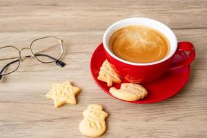 feliz natal com biscoitos caseiros e xícara de café no fundo da mesa de madeira. véspera de natal, festa, feriado e feliz ano novo conceito foto