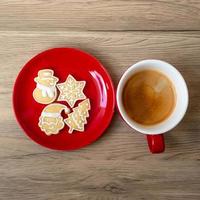 feliz natal com biscoitos caseiros e xícara de café no fundo da mesa de madeira. véspera de natal, festa, feriado e feliz ano novo conceito foto