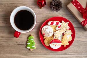 feliz natal com biscoitos caseiros e xícara de café no fundo da mesa de madeira. véspera de natal, festa, feriado e feliz ano novo conceito foto