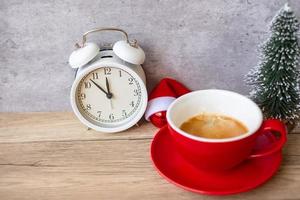 café expresso quente e relógio vintage na mesa, xícara de café vermelha no café ou em casa pela manhã. atividade, rotina diária, manhã, treino e conceito de equilíbrio de vida profissional foto