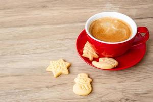 feliz natal com biscoitos caseiros e xícara de café no fundo da mesa de madeira. véspera de natal, festa, feriado e feliz ano novo conceito foto