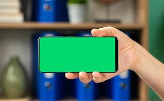 mulher segurando um celular com tela verde horizontal foto