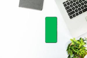 smartphone com tela verde em uma mesa com laptop foto