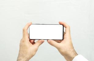 segurando um smartphone com tela branca horizontal foto